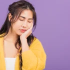 Young woman with jaw pain, illustrating how braces fix jaw alignment issues.